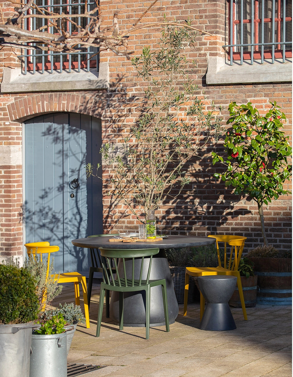 Ash Polypropylene Chair Army Green with Matching Chair in Yellow and Round Table in Outdoor Setting