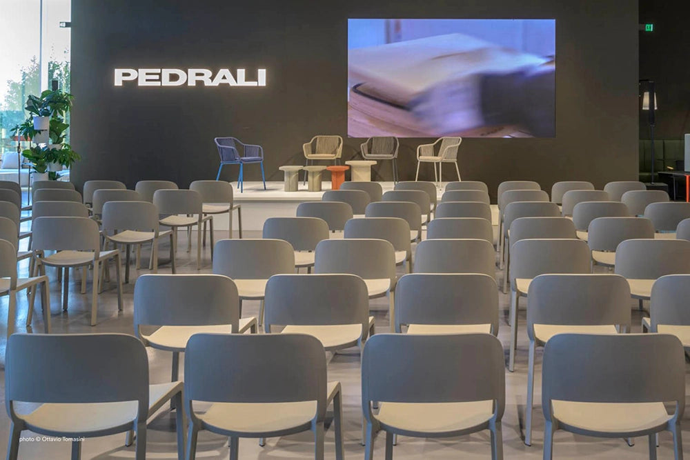 Babila Twist Dining Chair with Armrests in Beige Finish with Indoor Plant in Auditorium Setting