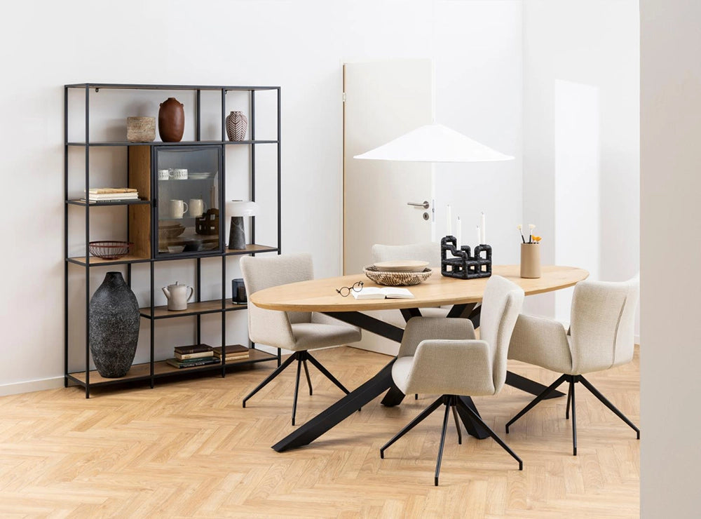 Evan Oval Dining Table in Oak Black Finish with White Lounge Chair and Metal Frame Shelf in Breakout Setting