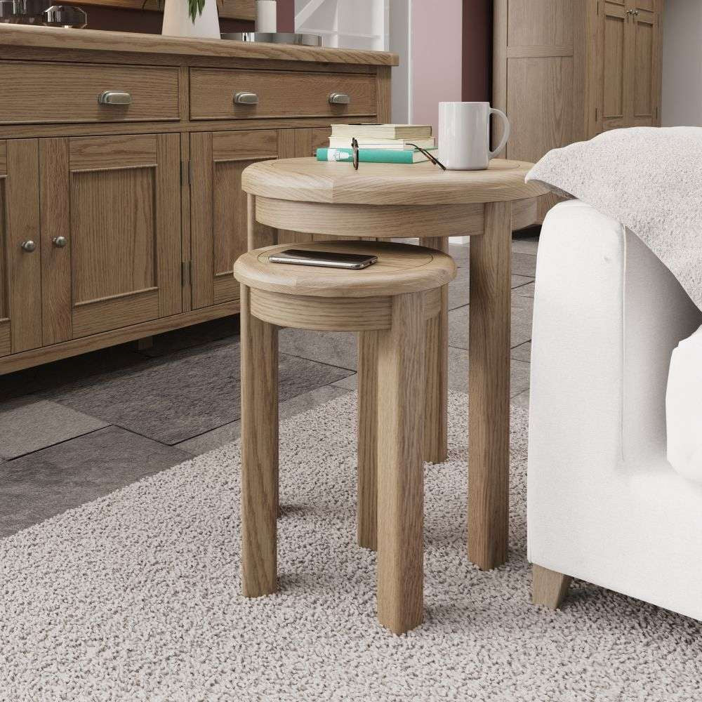 Haven Round Nest of 2 Tables in Warm Oak Finish with Wooden Cupboard and Sofa in Living Room Setting