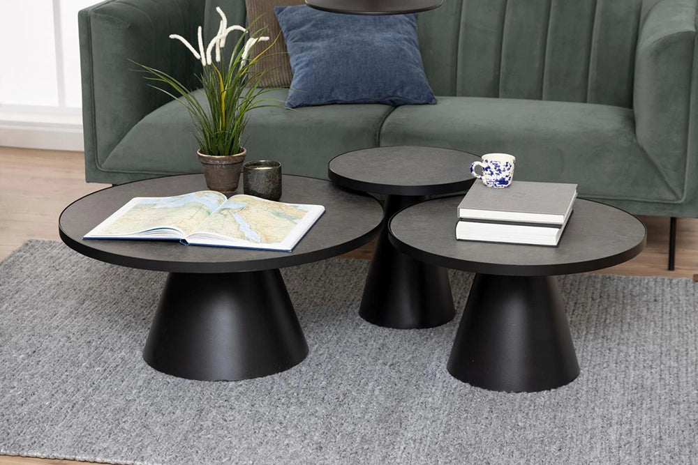 Lola Round Coffee Table in Black Finish with Upholstered Sofa and Books in Living Room Setting