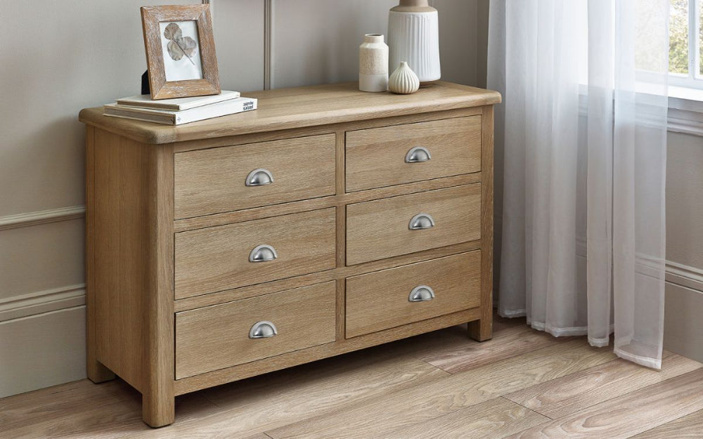 Marissa 6 Drawer Wide Chest in Limed Oak Finish with Flower Vase and Books in Bedroom Setting 2