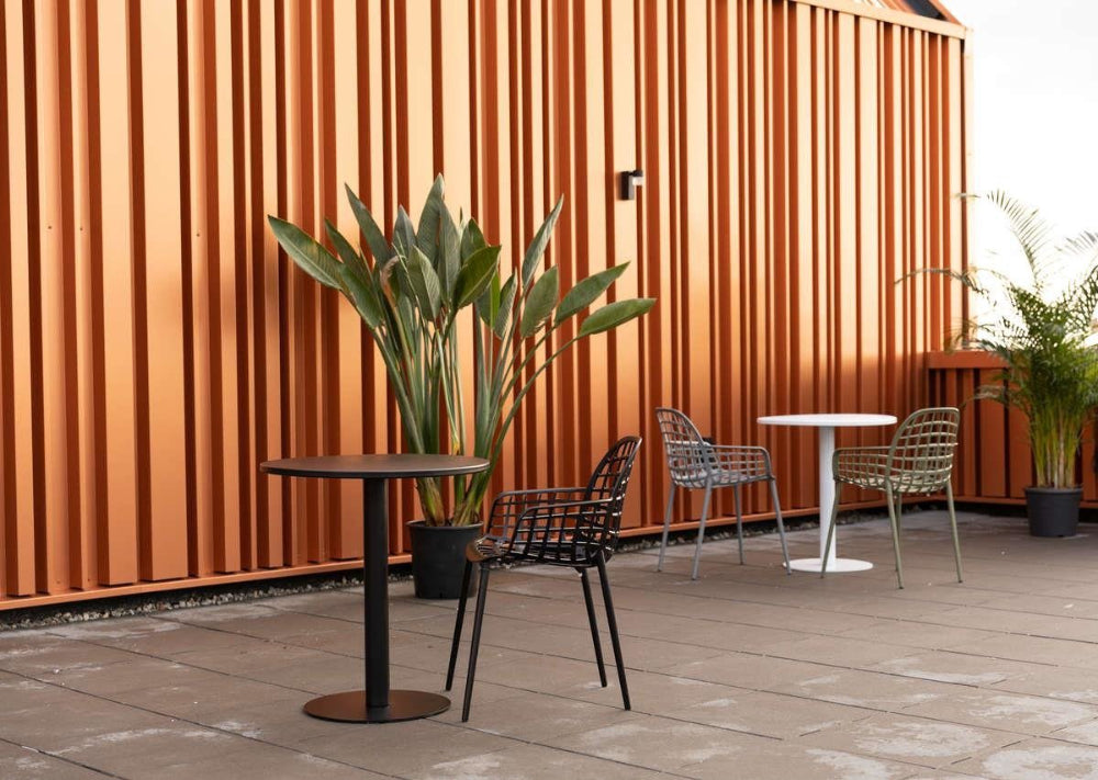 Miles Outdoor Dining Table in Black Finish with Plant and Chairs in Outdoor Setting
