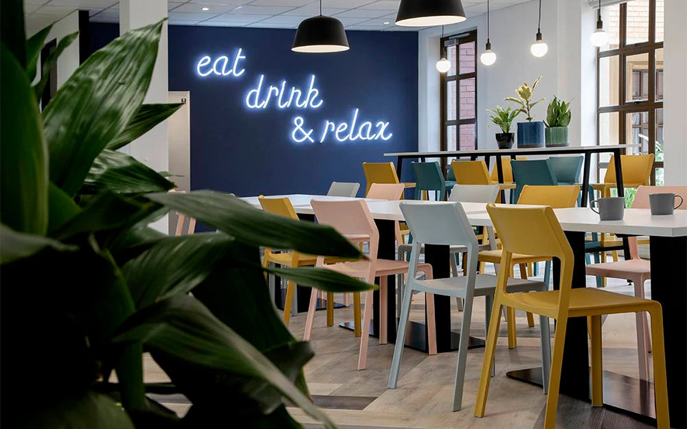 Nardi Thrill Stackable Monobloc Chair with Armrest in Different Finishes with Long Table in Cafeteria