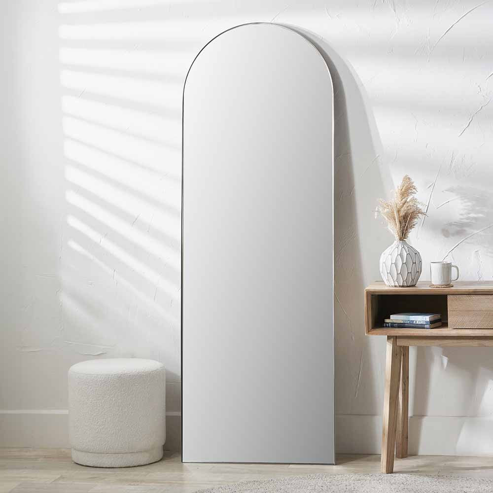 Peyton Silver Metal Slim Frame Arch Floor Mirror with Pouffe and Side Table in Bedroom Setting