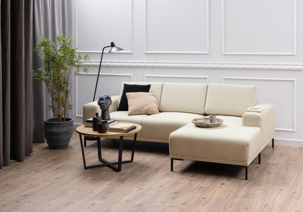 Ramble Round Coffee Table in Wild Oak Finish with Corner Sofa and Lamp in Living Room Setting