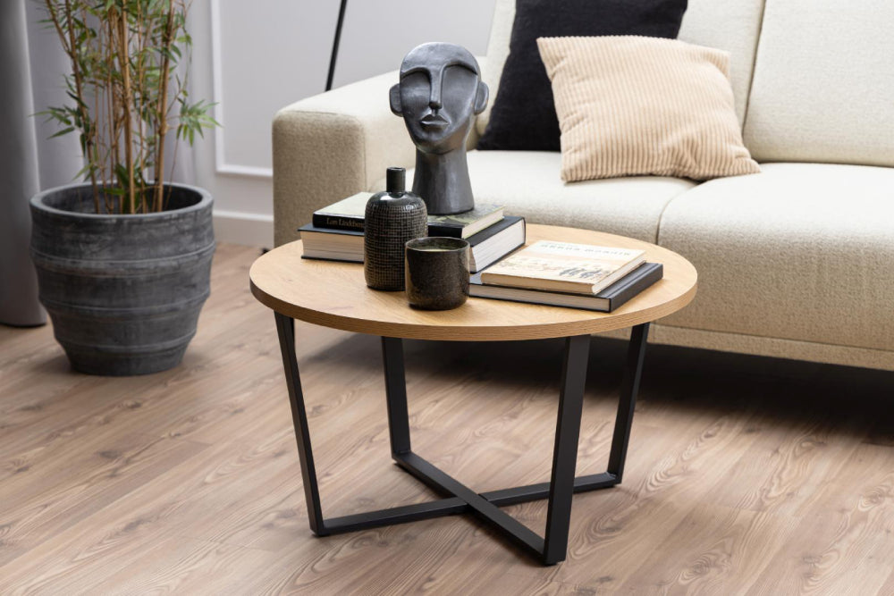 Ramble Round Coffee Table in Wild Oak Finish with Corner Sofa and Plant in Living Room Setting