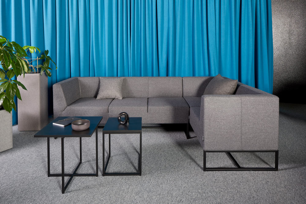 Verso-Upholstered-Modular-Sofa-in-Grey-Finish-with-Black-Coffee-Table-and-Indoor-Plant-in-Breakout-Setting.webp