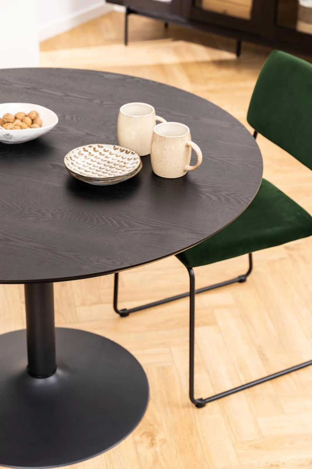 Antonio Round Dining Table in Black Finish with Upholstered Chair and Coffee Cup in Living Room Setting
