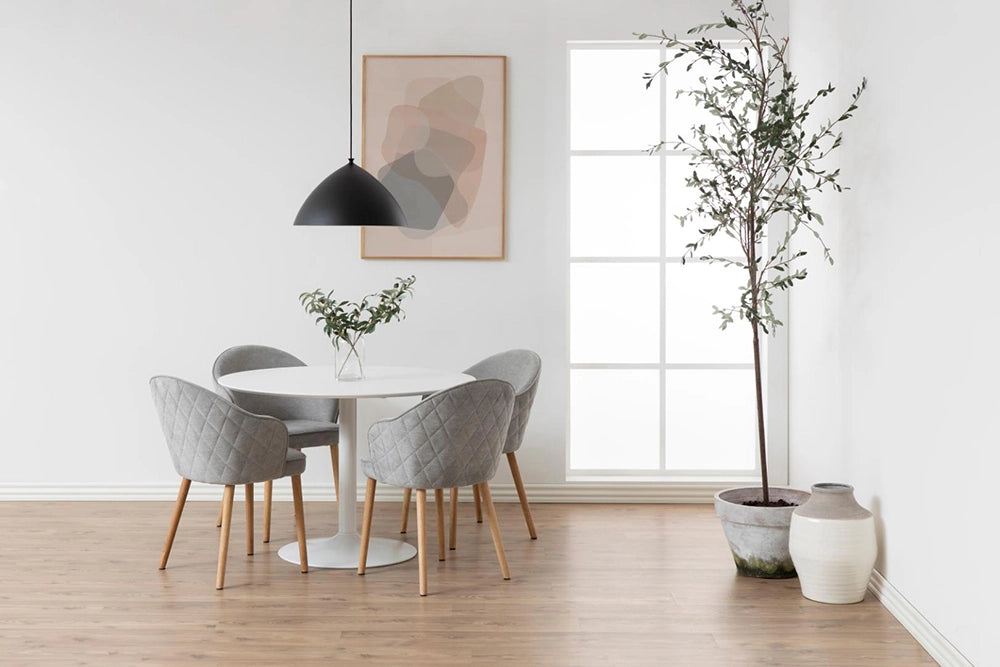 Antonio Round Dining Table in White Finish with Upholstered Grey Chair and Indoor Plant in Breakout Setting