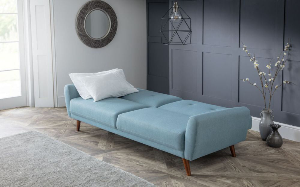 Capri Sofa Bed Blue with White Pillows and Wall Mirror in Living Room Setting