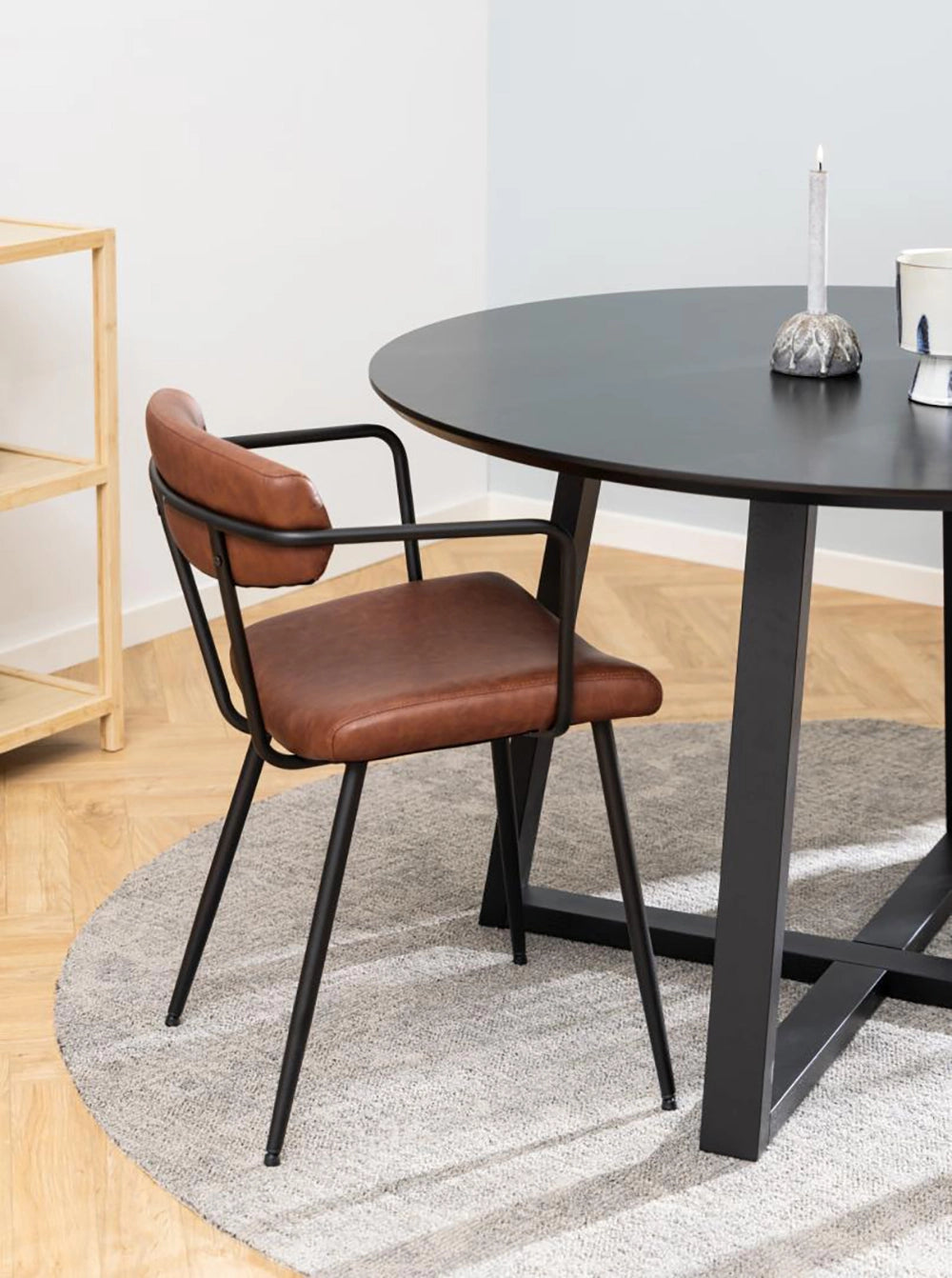 Court Round Dining Table in Black Finish with Brown Armchair and Lighted Candle in Living Room Setting