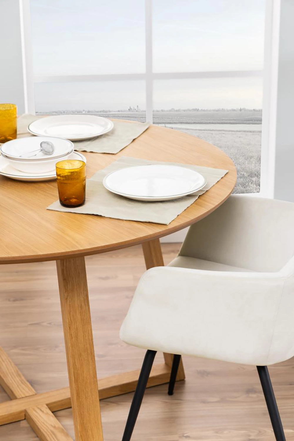 Court Round Dining Table in Oak Finish with White Upholstered Chair and Plate in Dining Setting