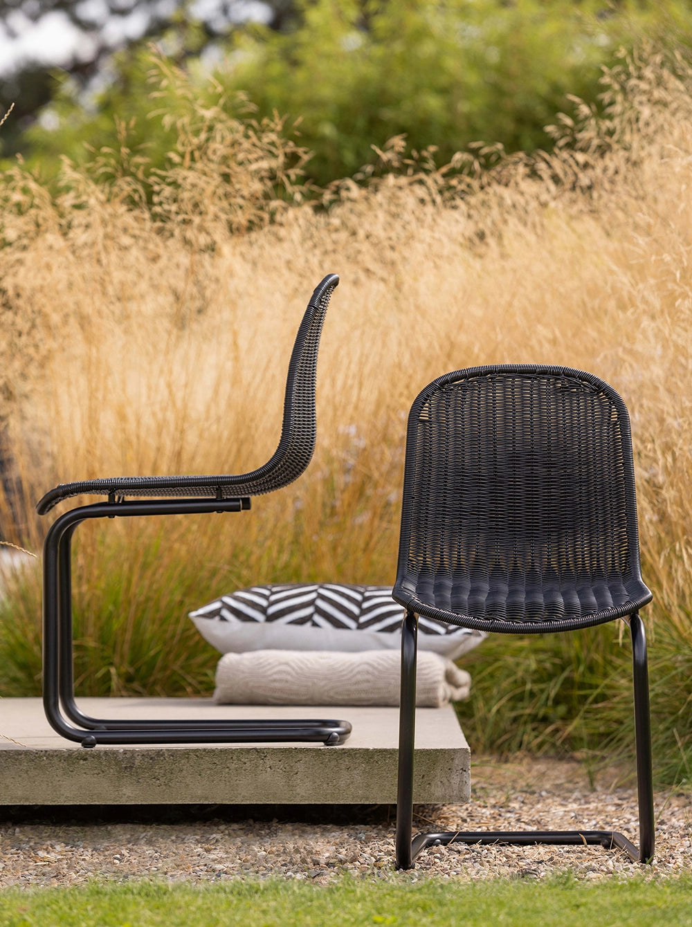 Elm Dining Chair - Black 8 with Concrete Platform and Printed Pillow in Outdoor Setting