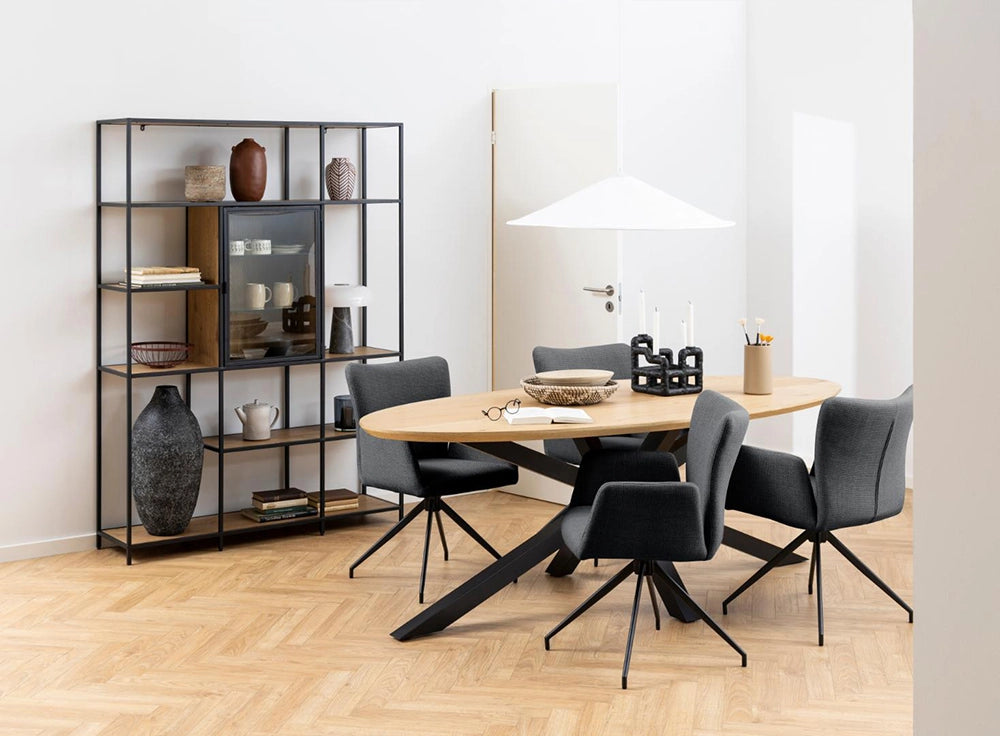 Evan Oval Dining Table in Oak Black Finish with Grey Lounge Chair and Metal Frame Shelf in Breakout Setting