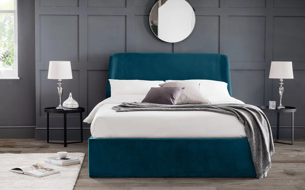 Fred Storage Ottoman Bed in Teal Finish with Table Lamp and Round Mirror in Bedroom Setting