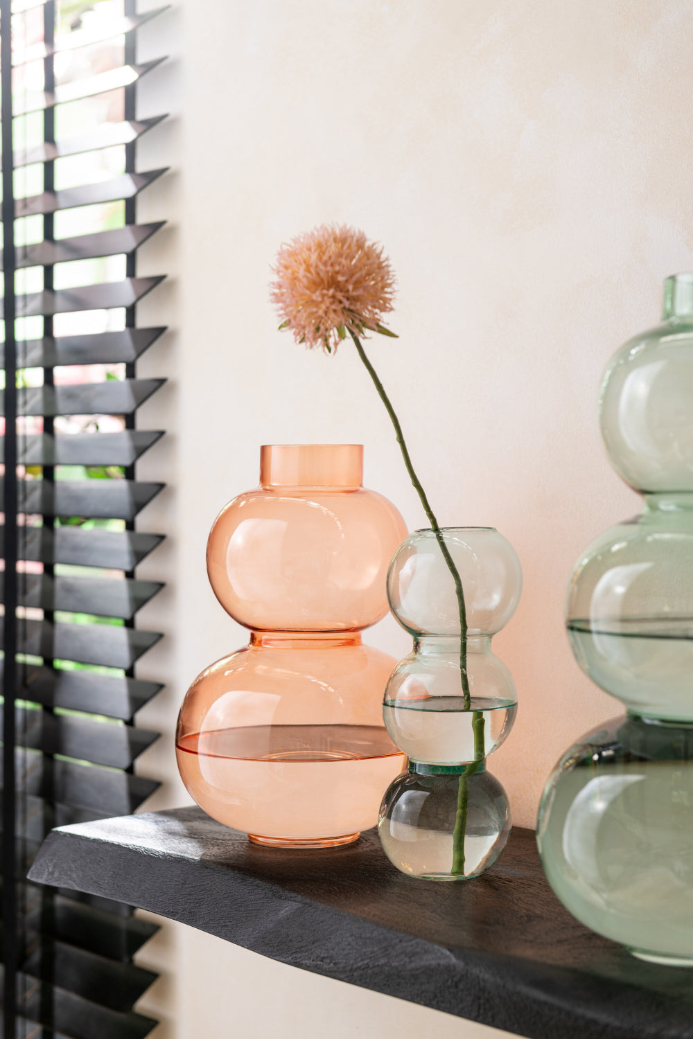 Glass Globe Shaped Small Vase in Orange Finish Beside Other Vases in Living Room Setting