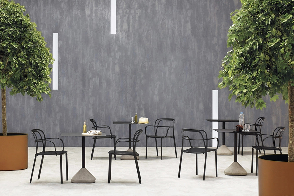 Intrigo Dining Chair with Armrests in Black Finish with Indoor Plant and Square Table in Outdoor Setting