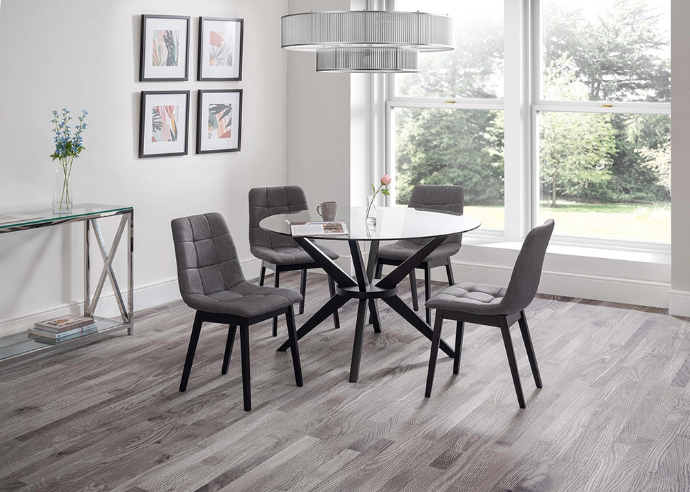 Jayden Round Dining Table in Glass Top with Padded Grey Chairs and Tansparent Vase in Breakout Setting 2