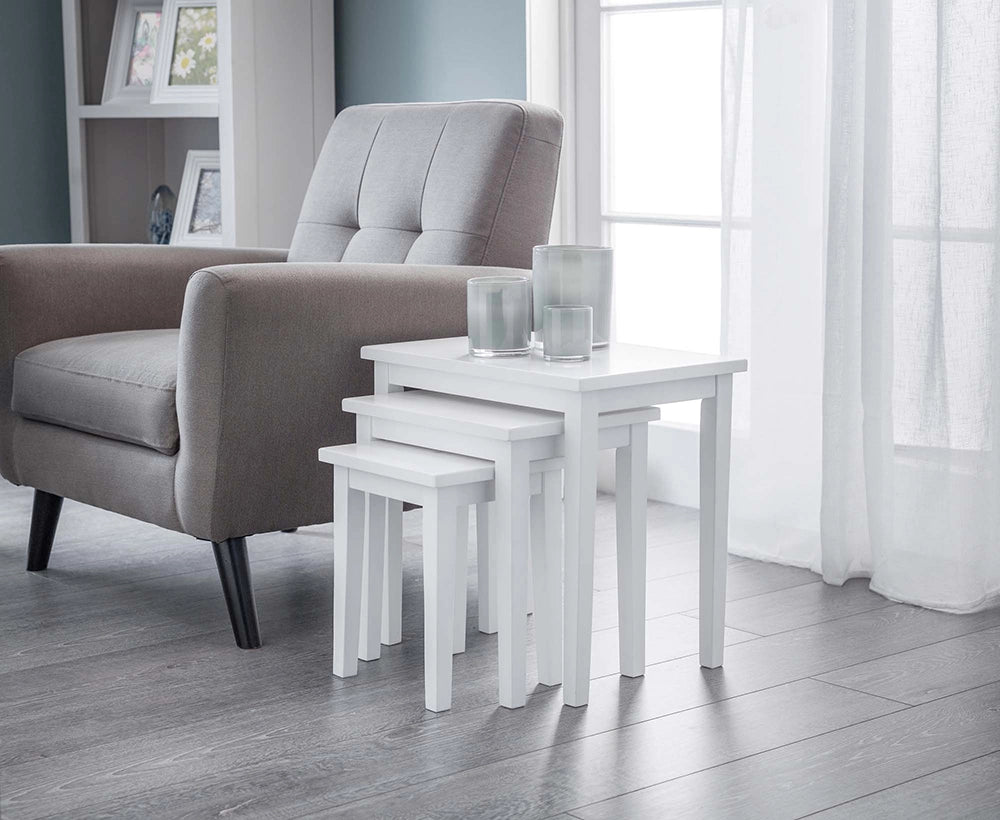 Lyon Nest Of Table in Pur White Finish with Upholstered Grey Armchair and Transparent Glass Candle in Living Room Setting