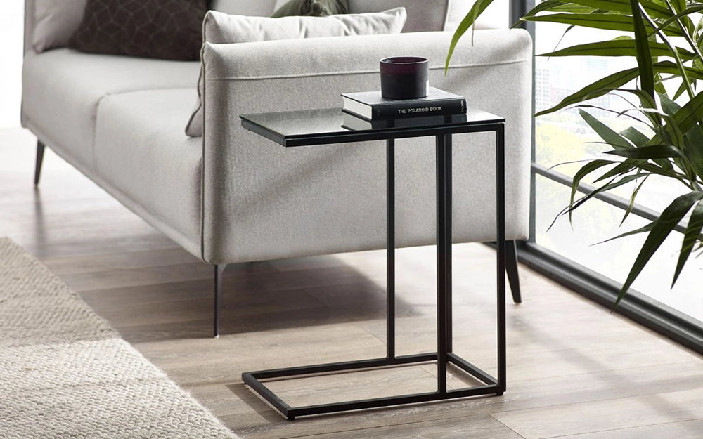 Manhattan Drinks Table Smoked Glass with Books and Indoor Plant in Living Room Setting
