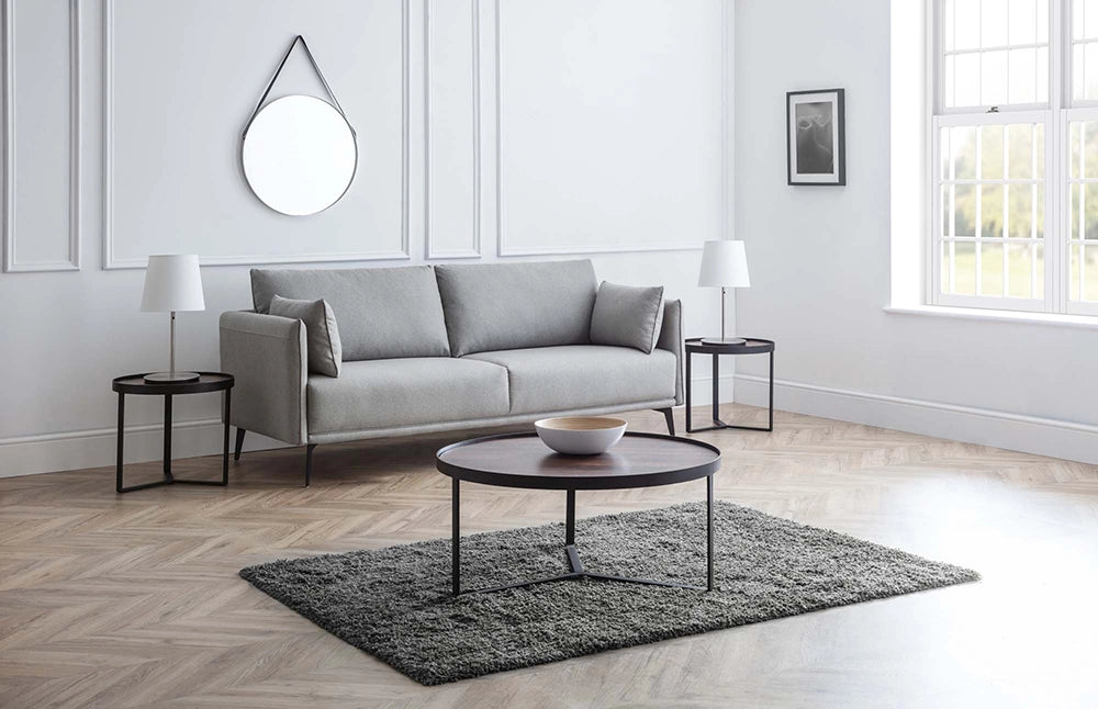 Skylar Coffee Table in Walnut Finish with Upholstered Grey Armchair and Table Lamp in Living Room Setting