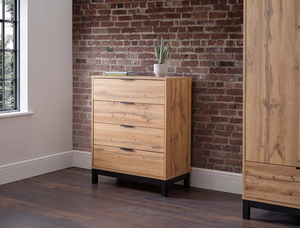 Verona 4 Drawer Chest in Wooden Finish with White Vase and Wardrobe in Bedroom Setting