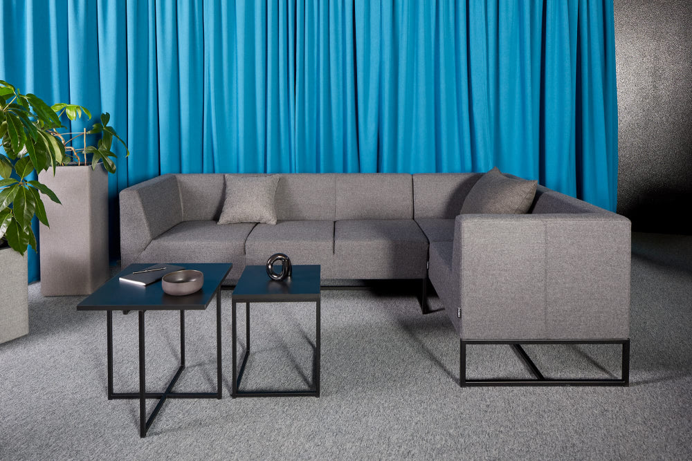 Verso Upholstered Modular Sofa in Grey Finish with Black Coffee Table and Indoor Plant in Breakout Setting